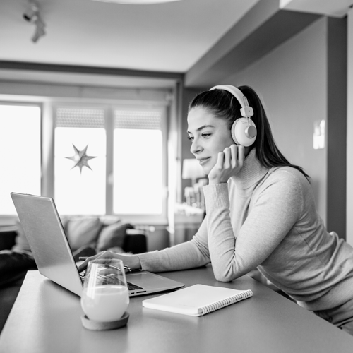 A woman sits at a computer with headphones on